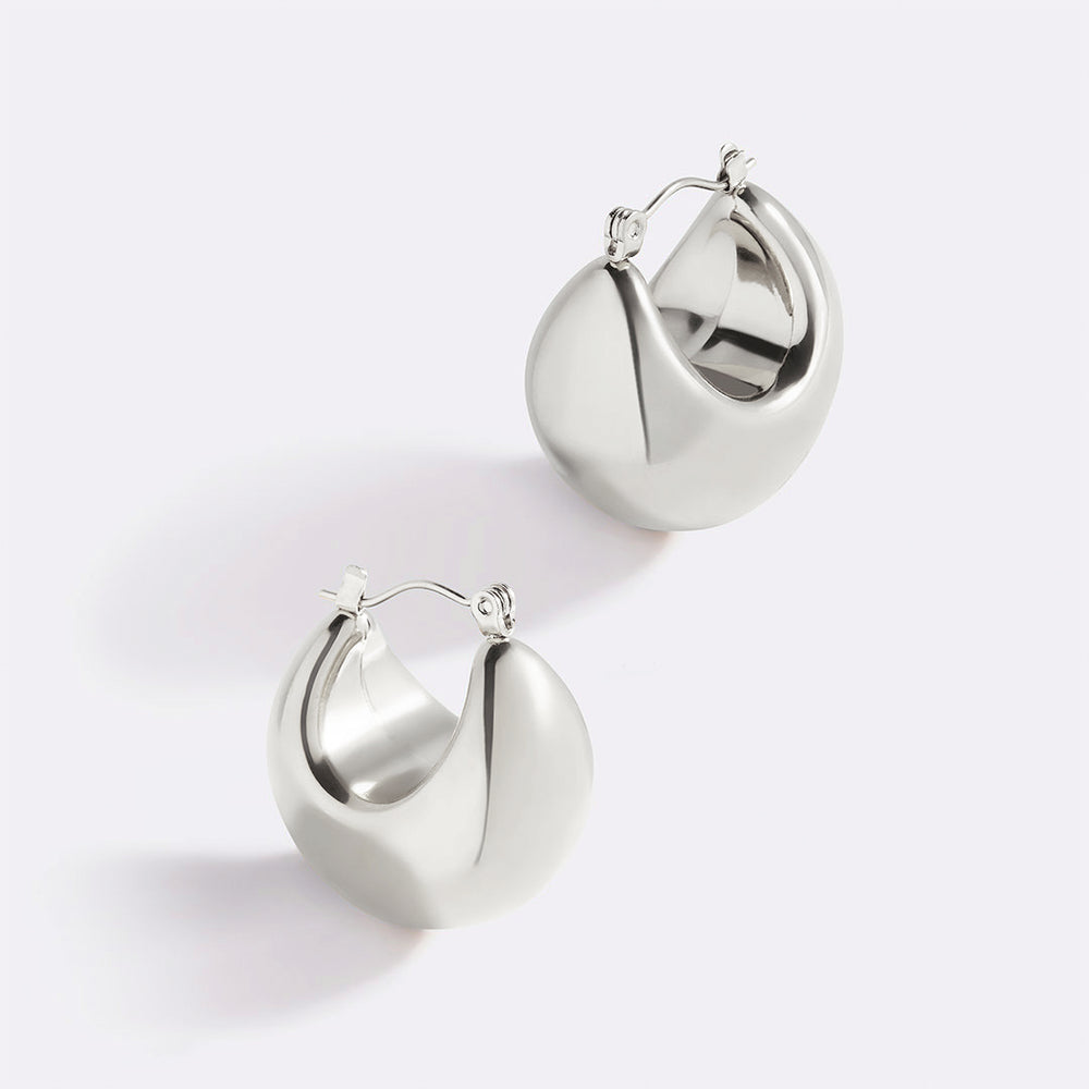 A pair of gold-colored sculpted hoop earrings against a white background.