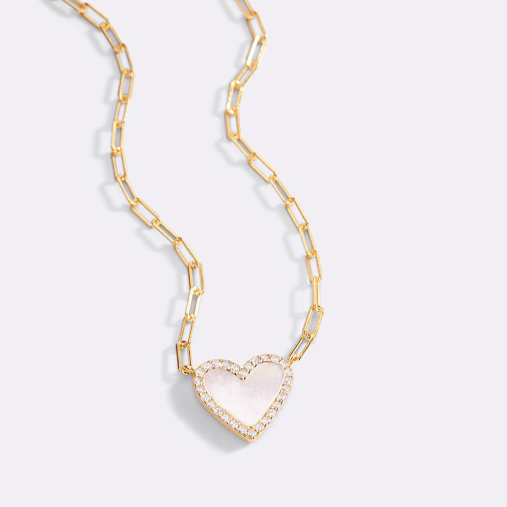 Gold chain necklace with a heart-shaped pendant on a light gray background