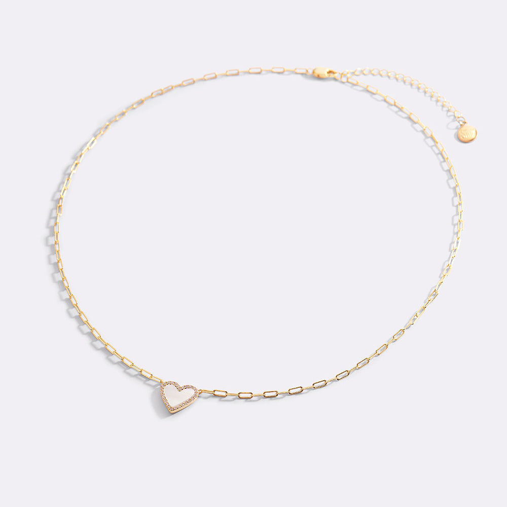 Gold necklace with a heart-shaped pendant on a light gray background