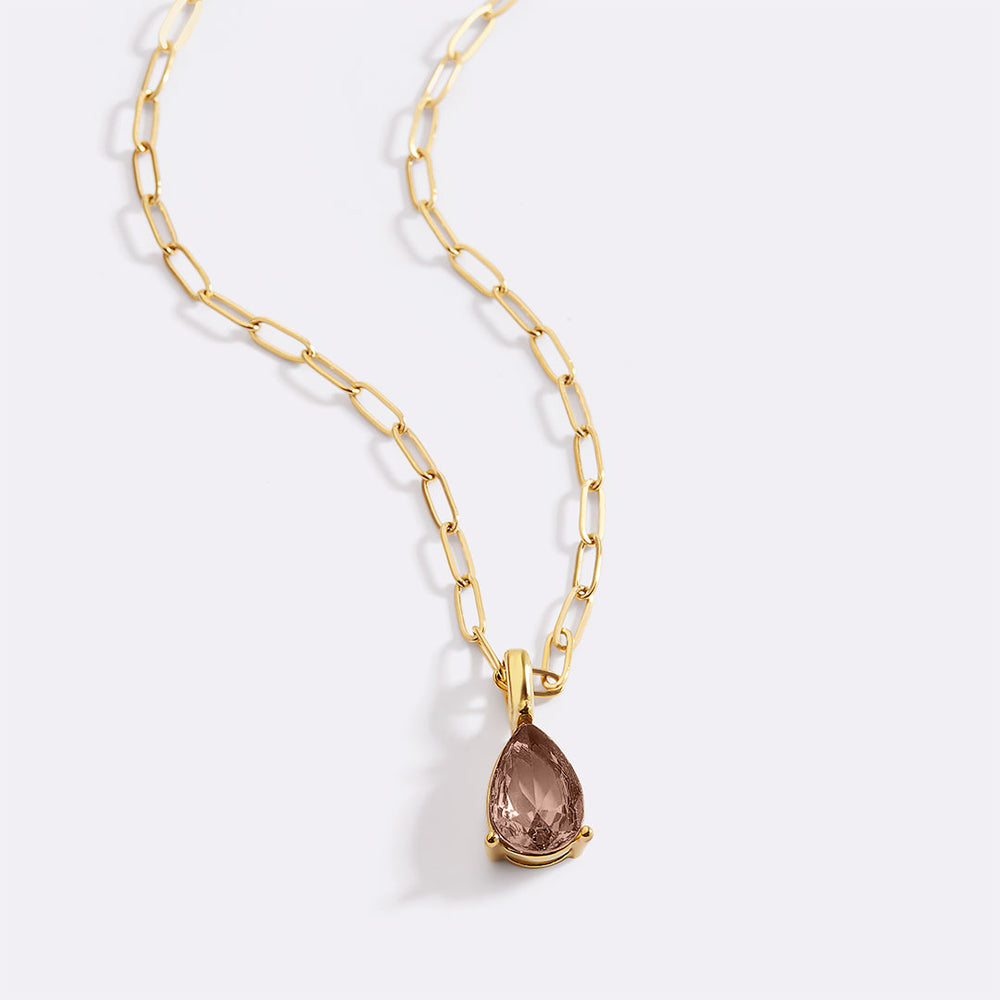 Gold necklace with a teardrop-shaped gemstone pendant on a white background