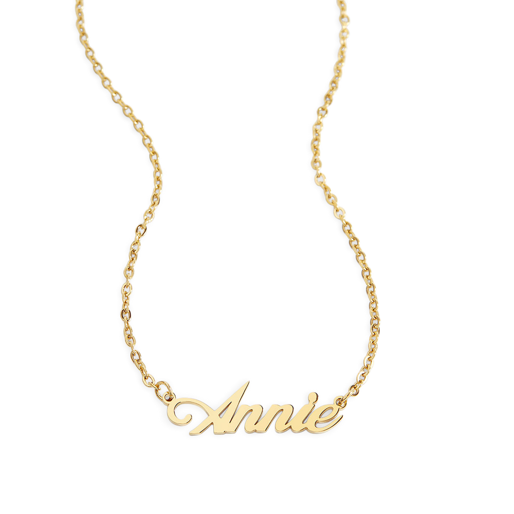 A gold name necklace with the name 'Annie' written in a cursive script on a chain.