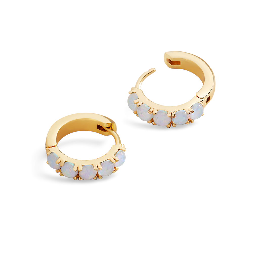 Gold hoop earrings with opal-like stones on a light gray background
