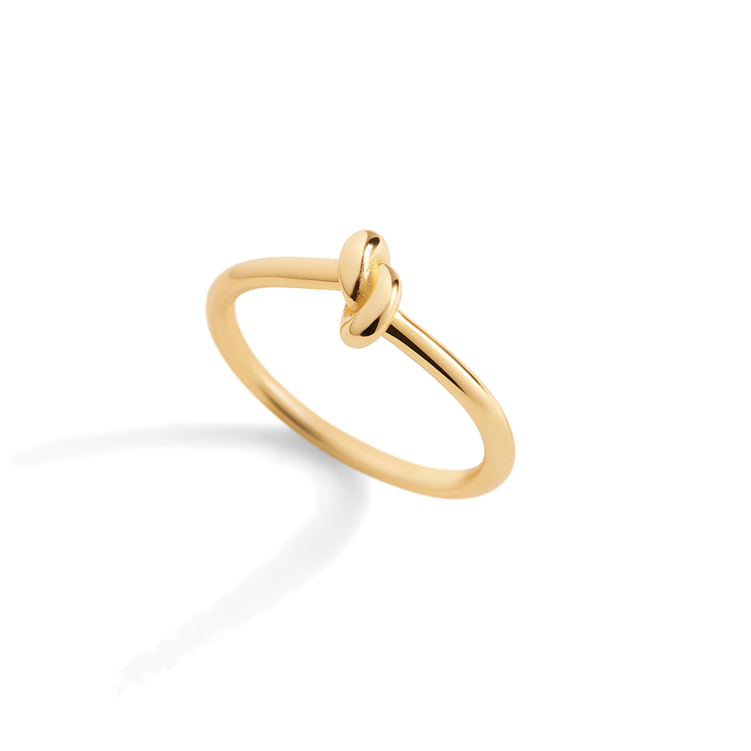 Gold ring with a knot design on a light gray background