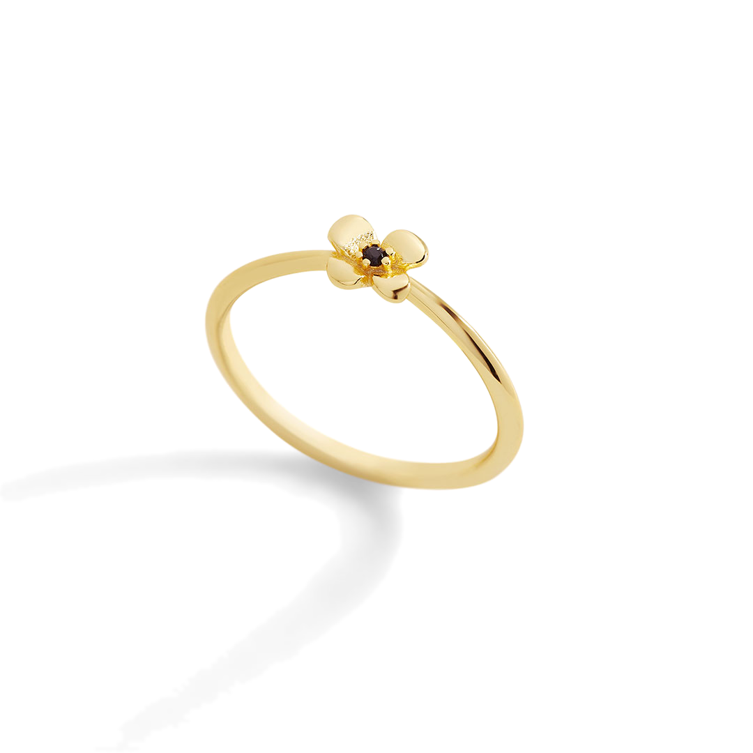 Gold ring with a small black gemstone on a light gray background
