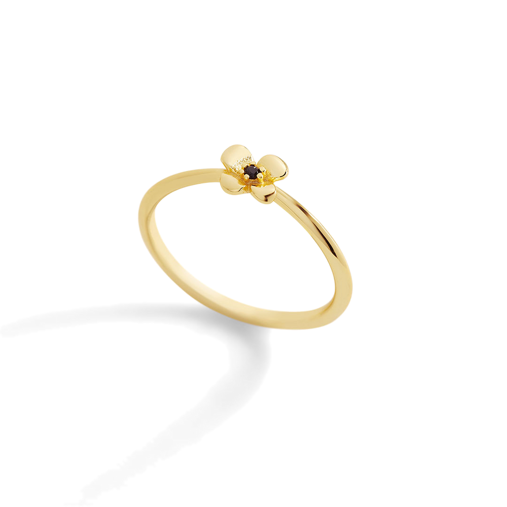 Gold ring with a small black gemstone on a light gray background