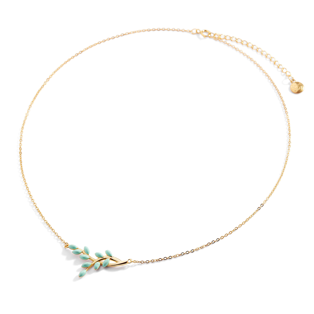 Delicate gold necklace with green leaf-like pendants on a light gray background