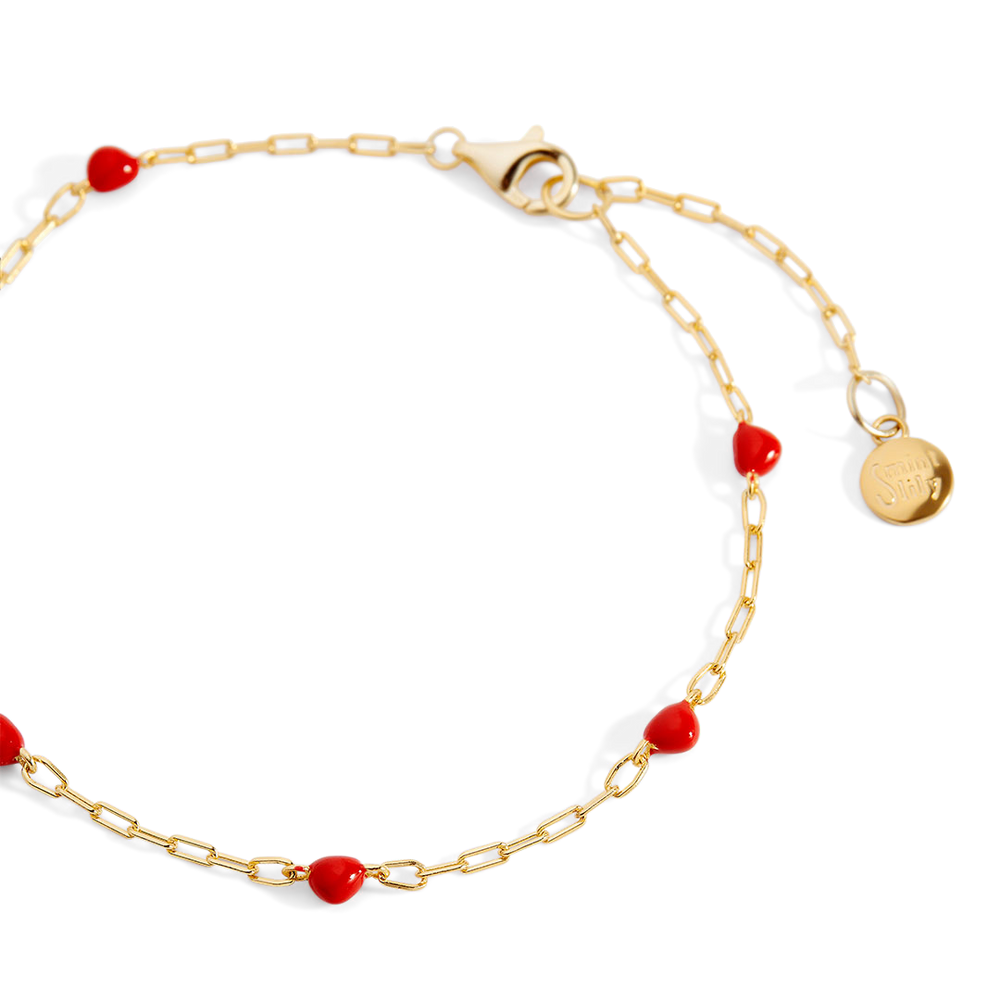 Gold bracelet with red beads on a white background