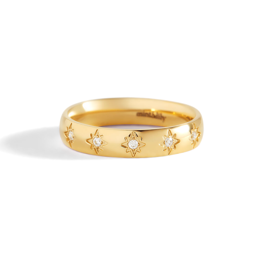 Gold ring with star-shaped diamond cutouts on a light gray background