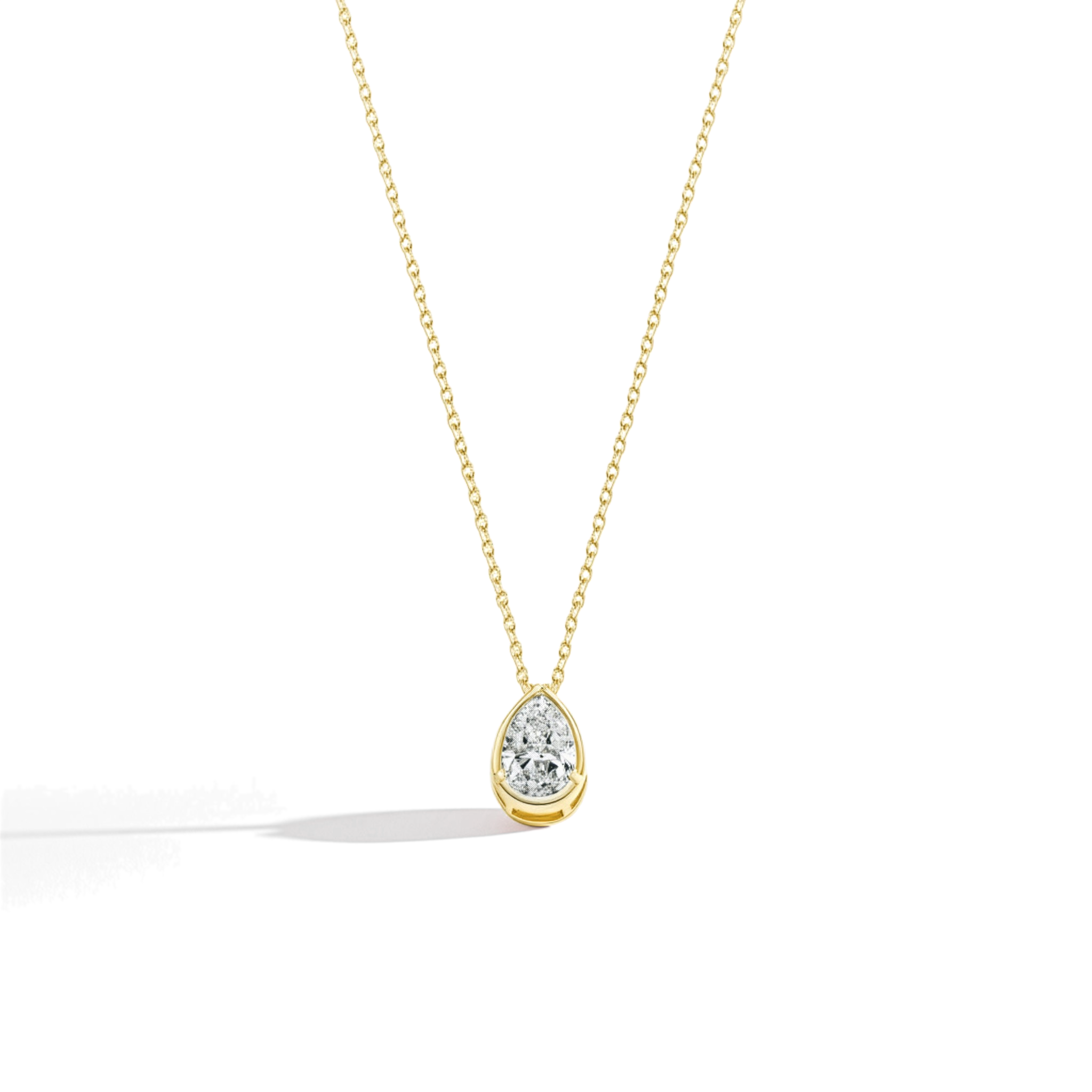 Gold necklace with a teardrop-shaped moissanite pendant on a light beige background