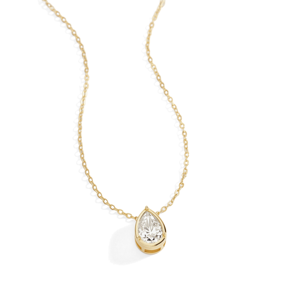 Gold necklace with a teardrop-shaped moissanite pendant on a light gray background