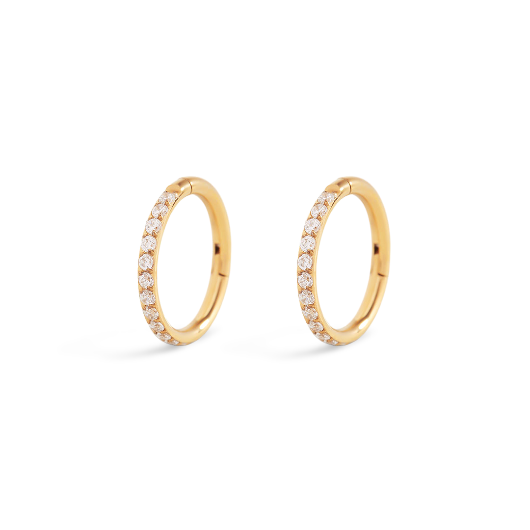 Pair of gold hoop earrings with embedded diamonds on a light gray background