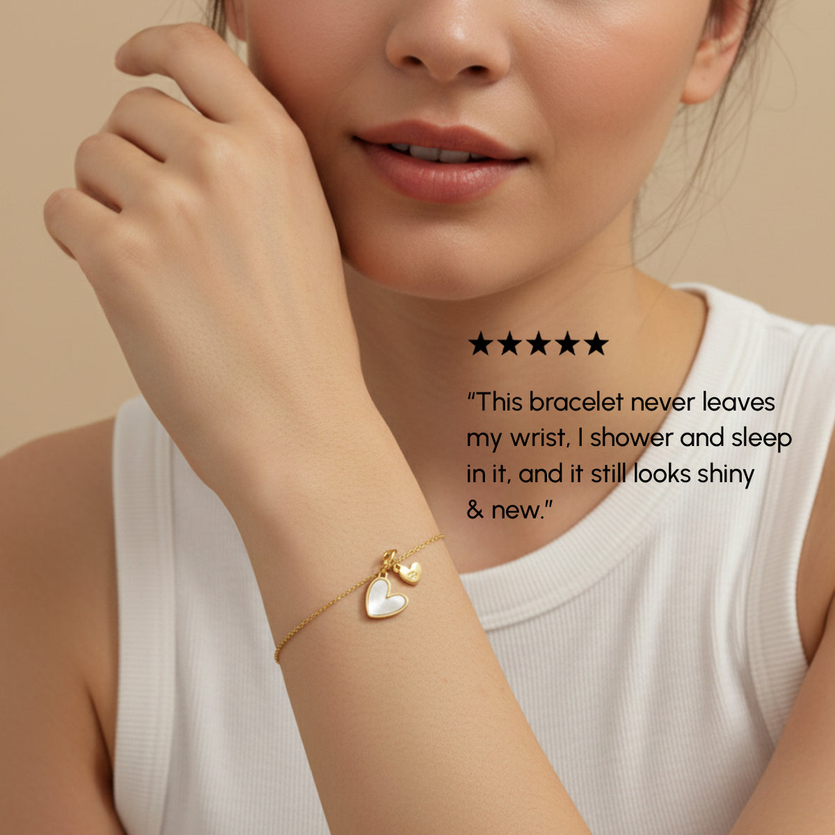 Woman wearing a gold bracelet with heart charms on a beige background