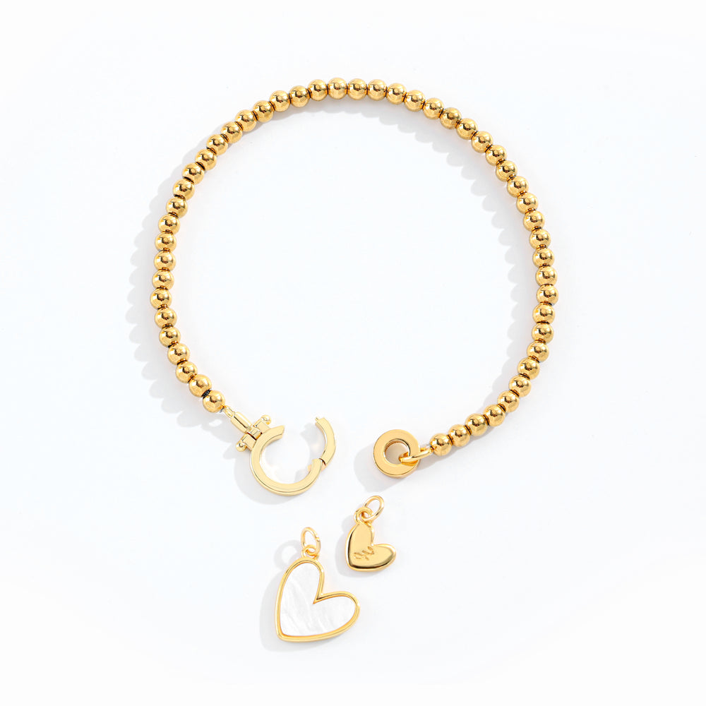 Gold bracelet with heart and crescent moon charms on a white background