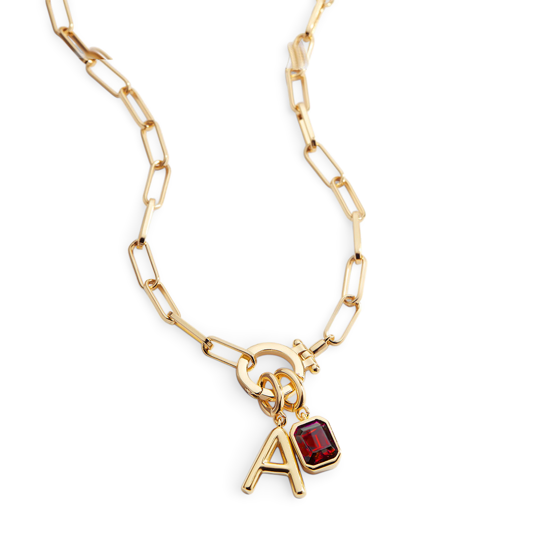 Gold necklace with a red gemstone and letter 'A' charm on a white background