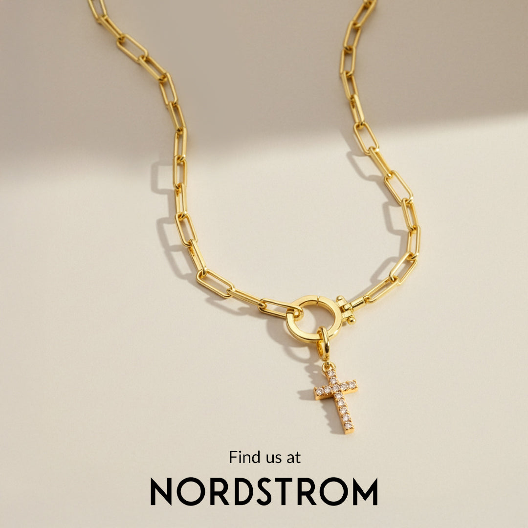 Gold chain necklace with a cross pendant on a beige background, Nordstrom branding visible.