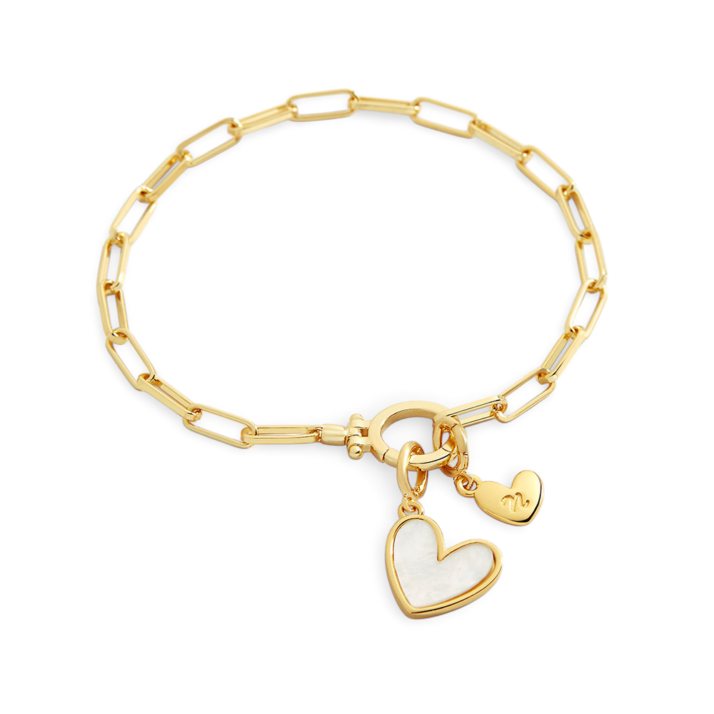 A gold bracelet with a heart-shaped charm and a customizable initial charm made from mother of pearl.
