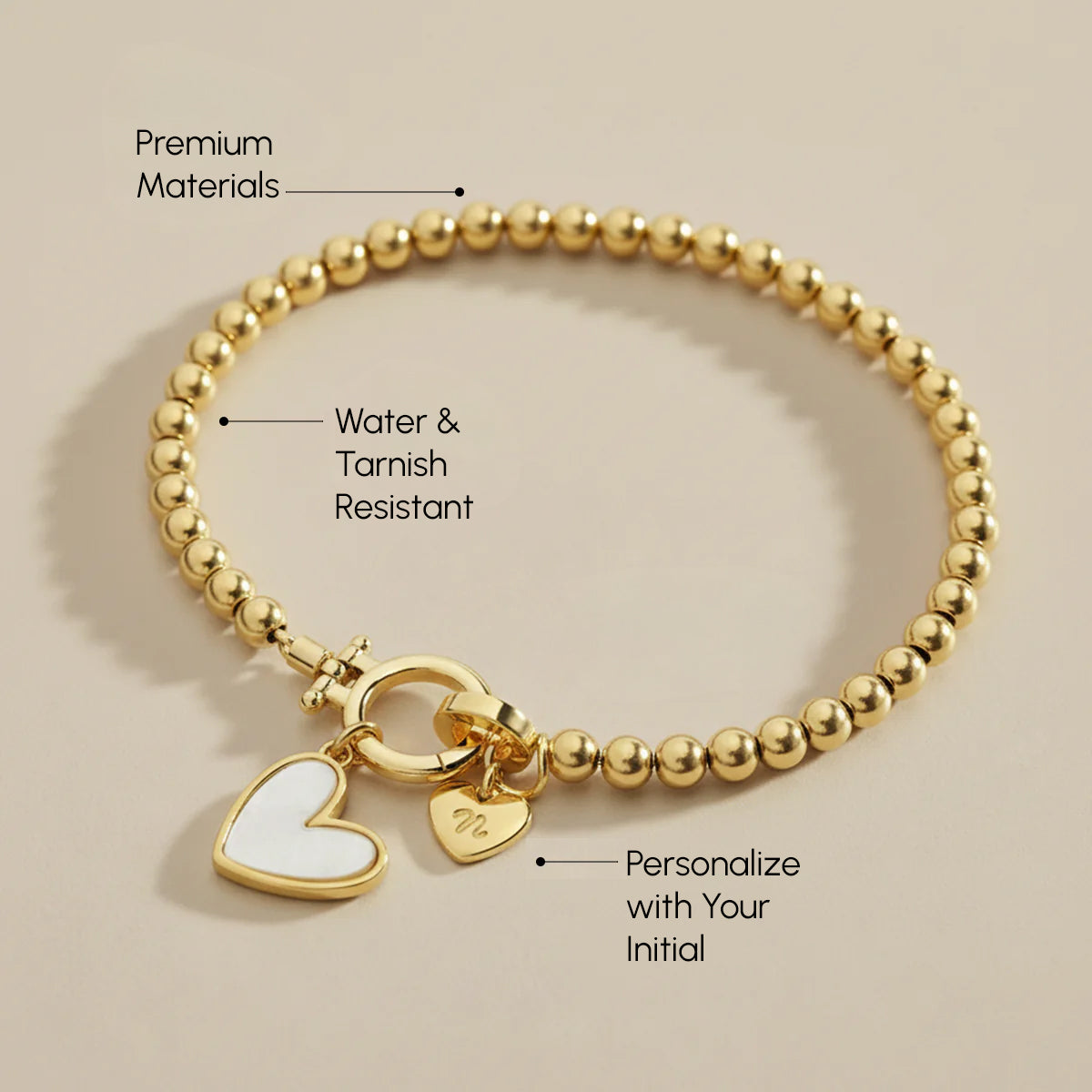 Gold bracelet with heart charm on a beige background