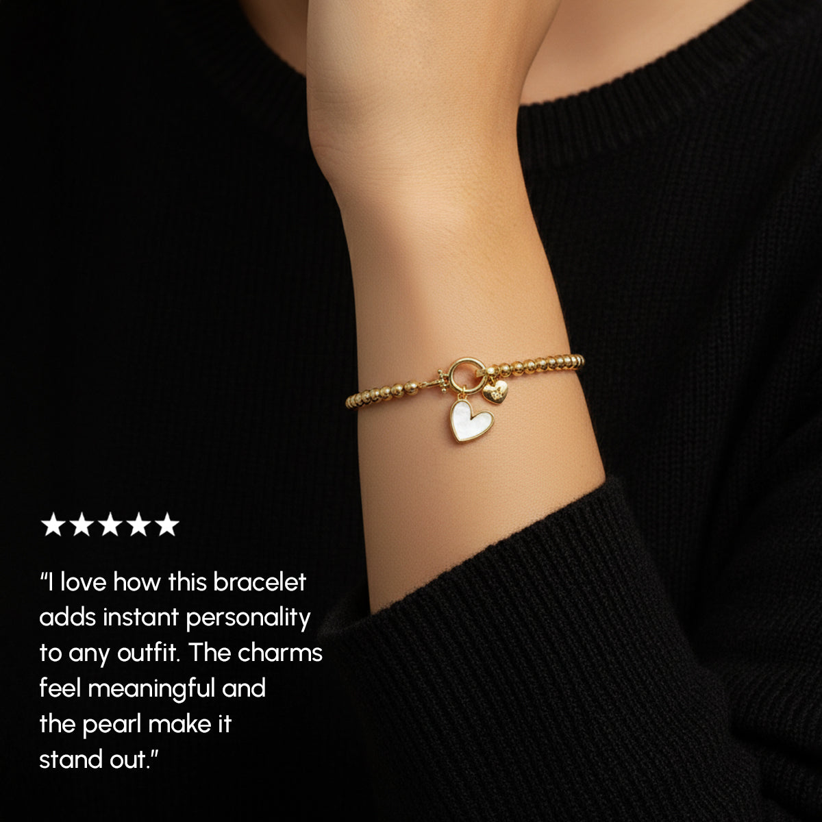 Gold bracelet with a heart charm on a wrist, against a black background