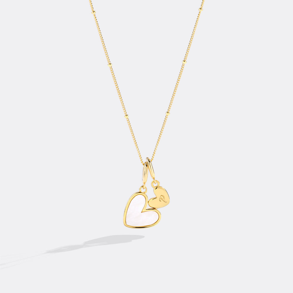 Gold heart-shaped necklace on a light gray background