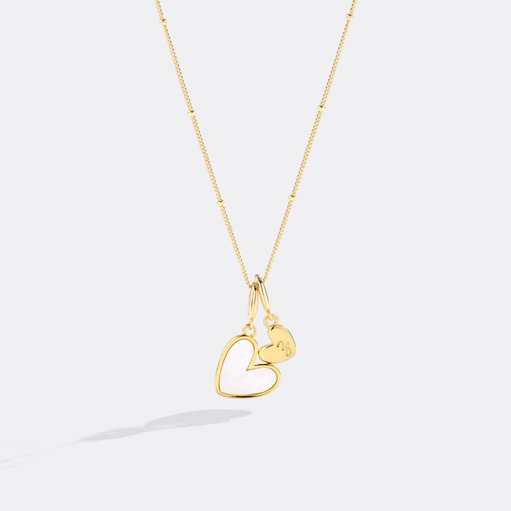 Gold heart-shaped pendant necklace on a light gray background