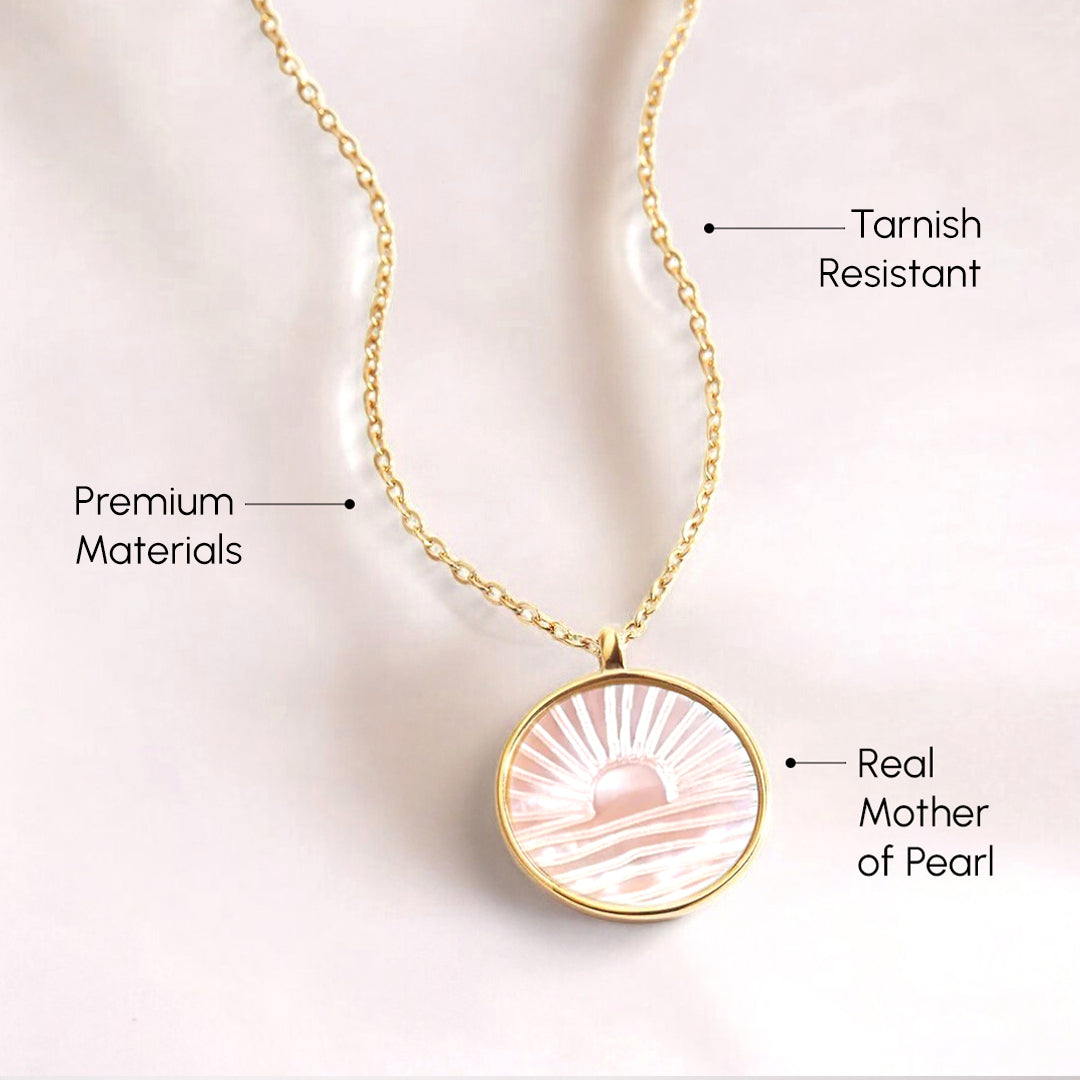Gold necklace with a pink pendant on a light background