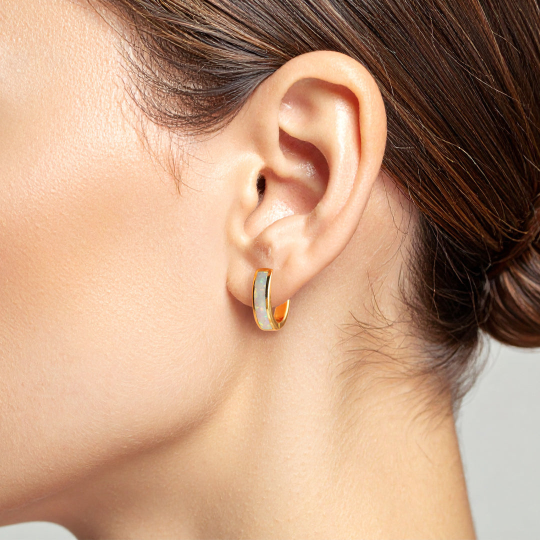 Close-up of an ear wearing a gold hoop earring with a blurred background