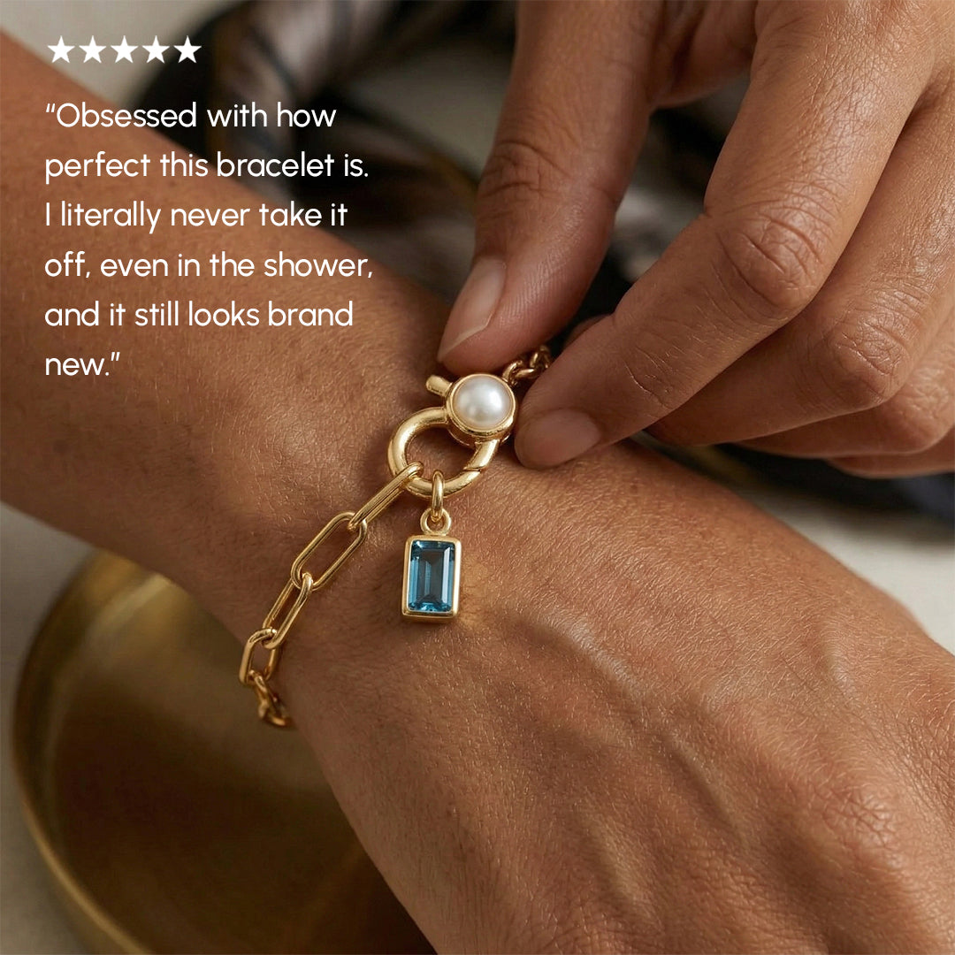 Gold bracelet with a pearl and blue gemstone worn on a wrist, with a five-star rating and customer review text.