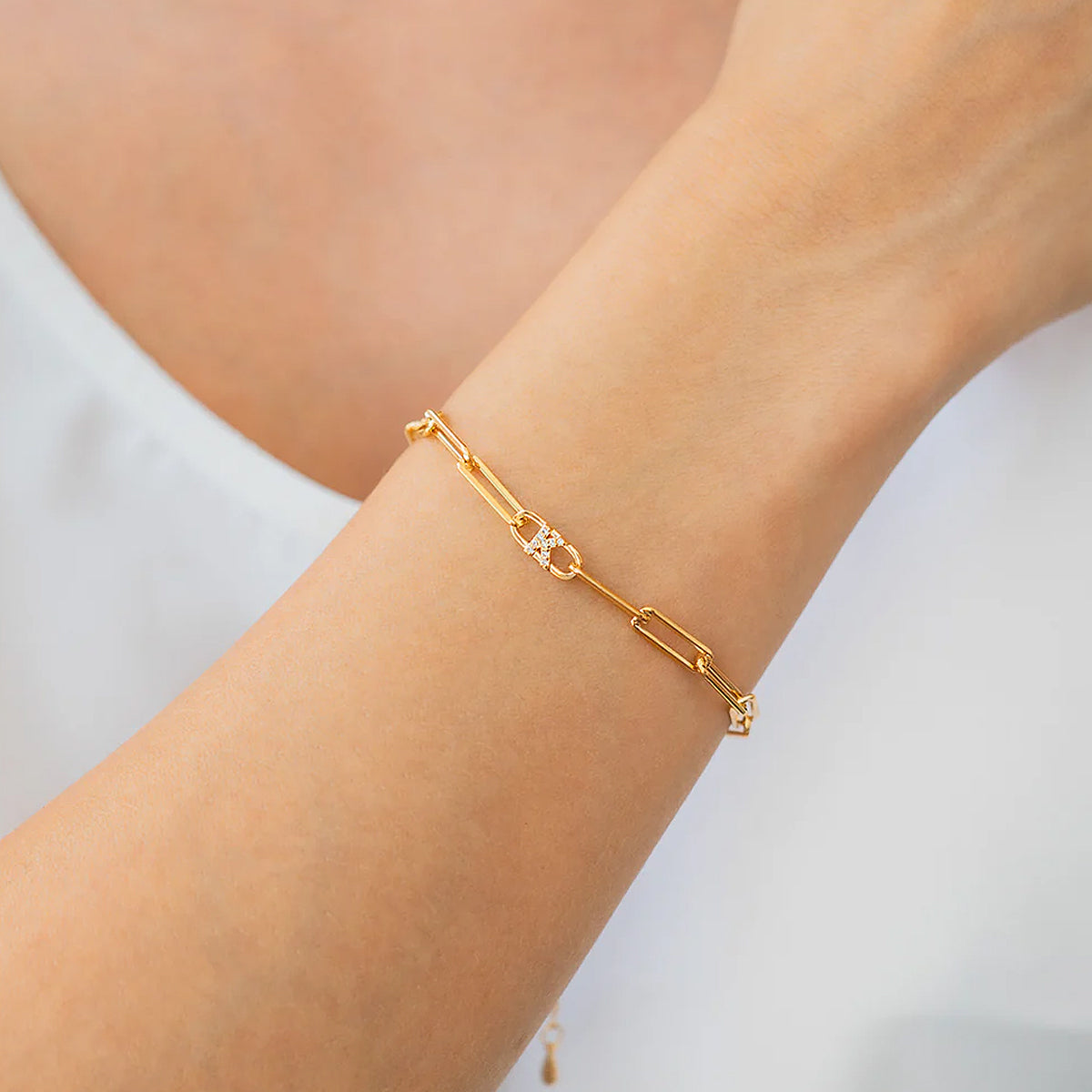 Gold bracelet on a person's wrist with a plain background