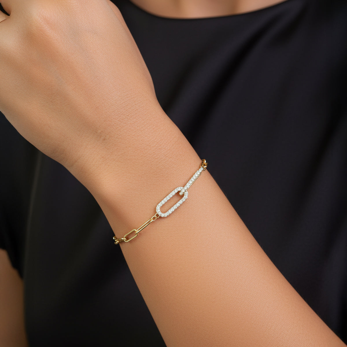 Gold bracelet with pearl accents on a wrist against a black background