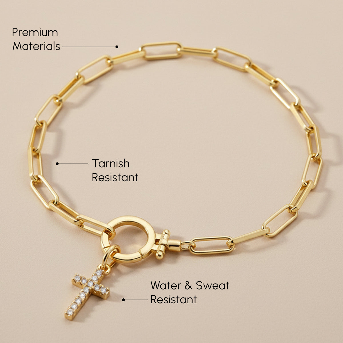 Gold bracelet with cross charm on a beige background