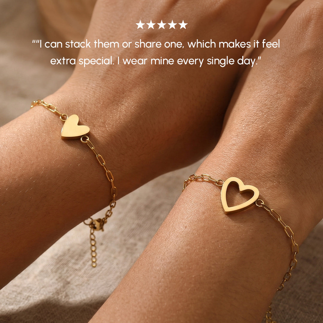 Gold heart-shaped bracelet on a wrist with a neutral background
