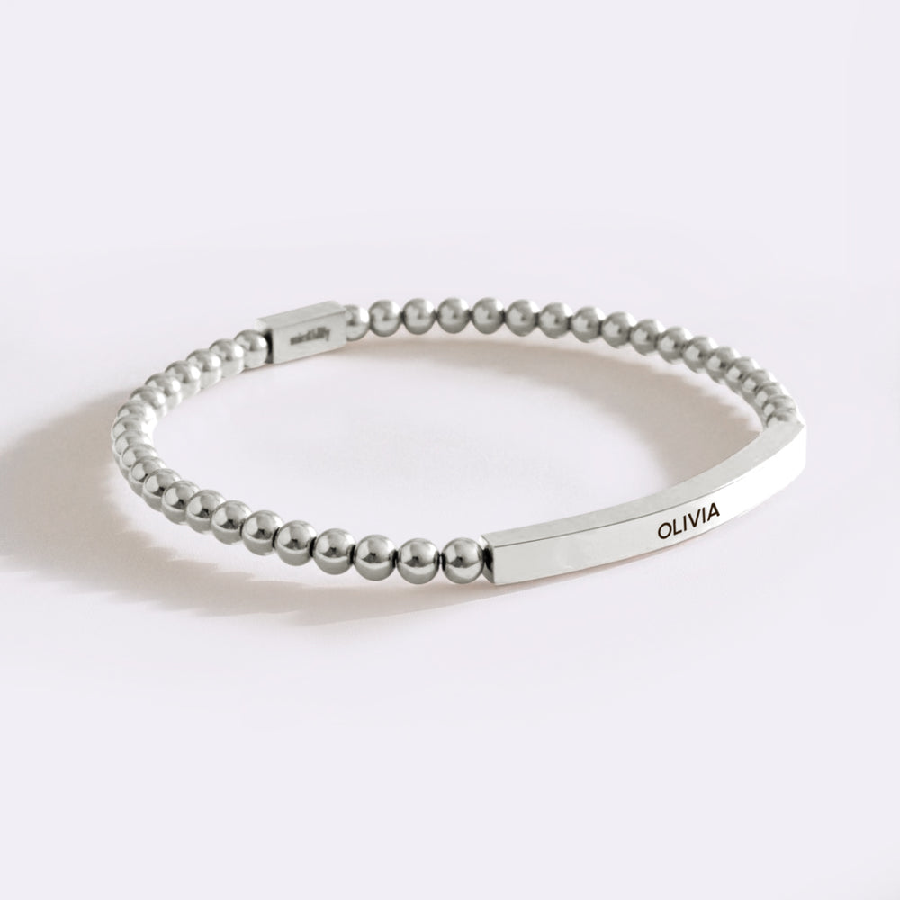 Silver beaded bracelet with engraved name on a white background