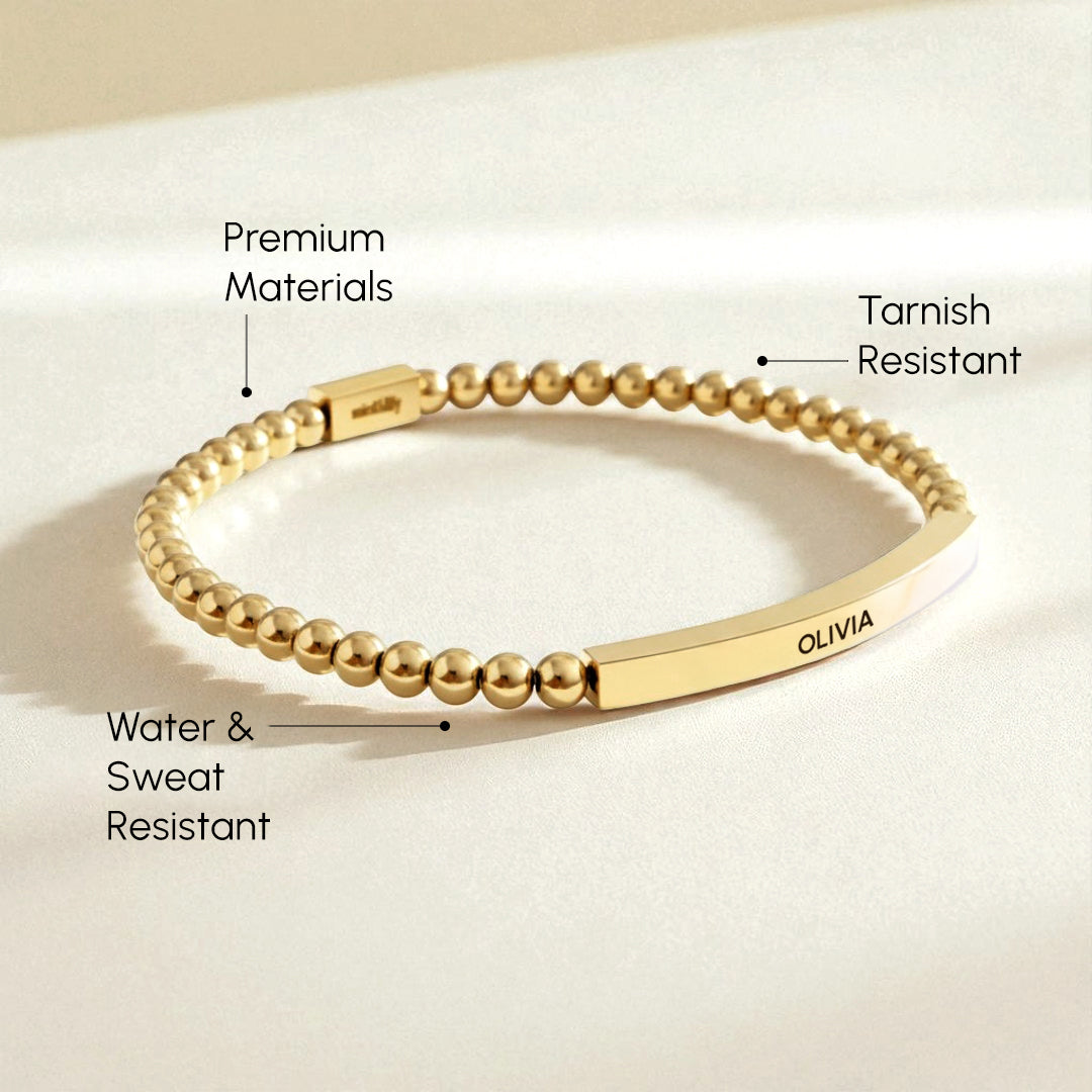 Gold bracelet with labeled features on a beige background