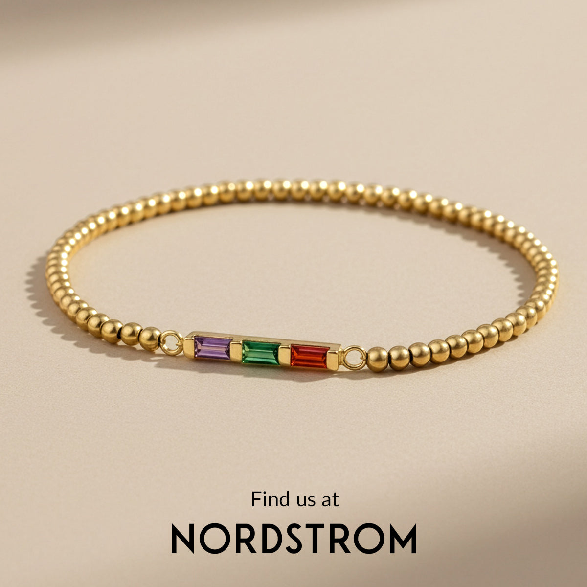 Gold bracelet with colored stones on a beige background, featuring Nordstrom branding.