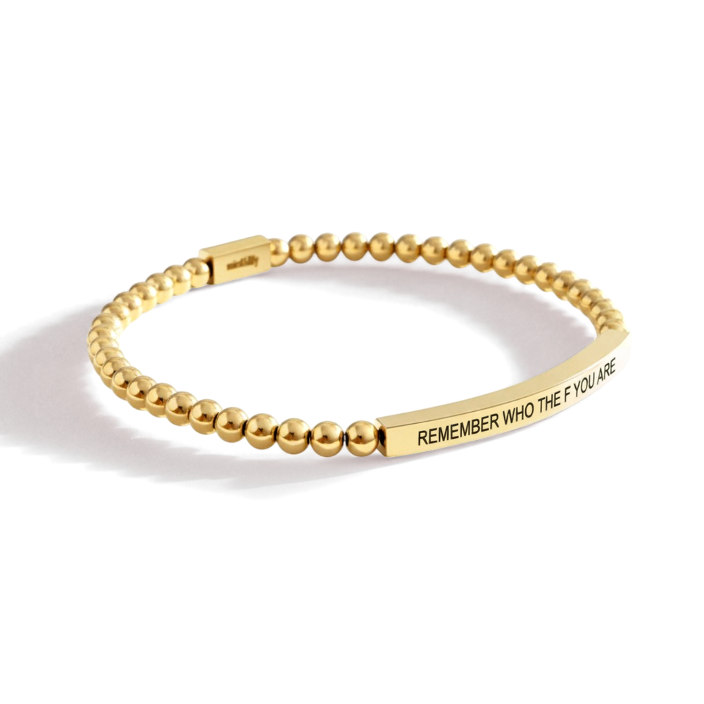 Gold beaded bracelet with engraved message on a white background