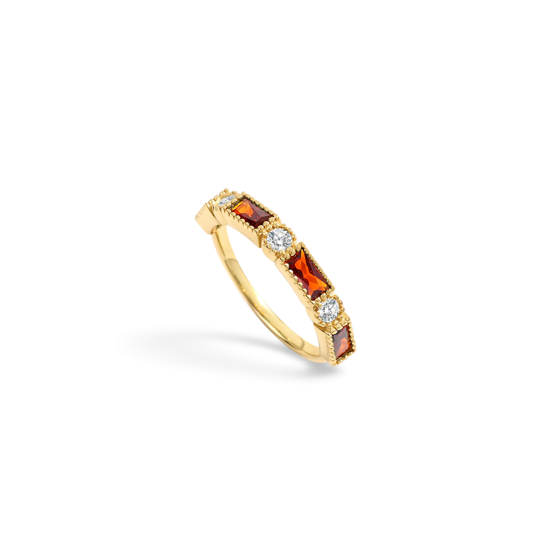 Gold ring with red gemstones and clear stones on a light gray background