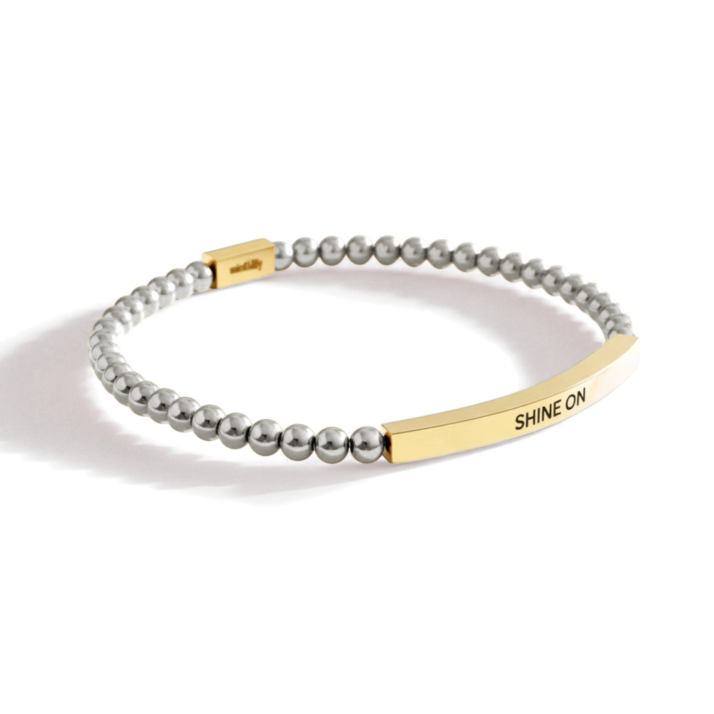 Bracelet with gold bar and 'SHINE ON' engraving on a white background