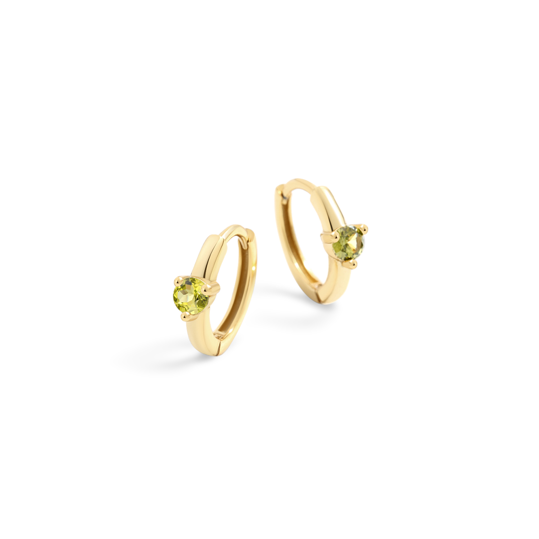 Gold hoop earrings with green gemstones on a white background