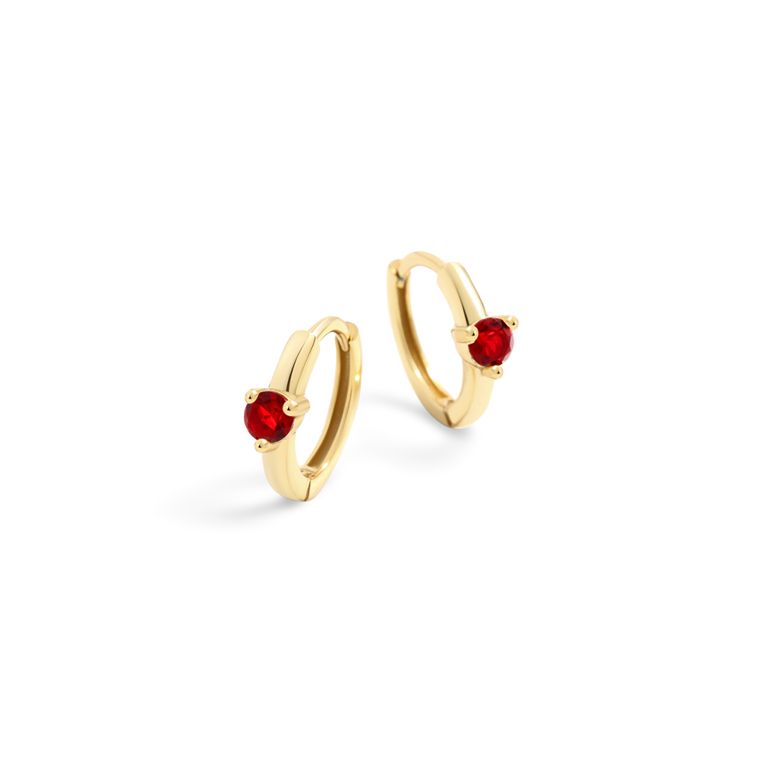 Gold hoop earrings with red gemstones on a white background