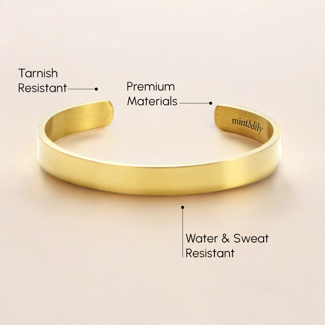 Gold bracelet with text highlighting features on a beige background