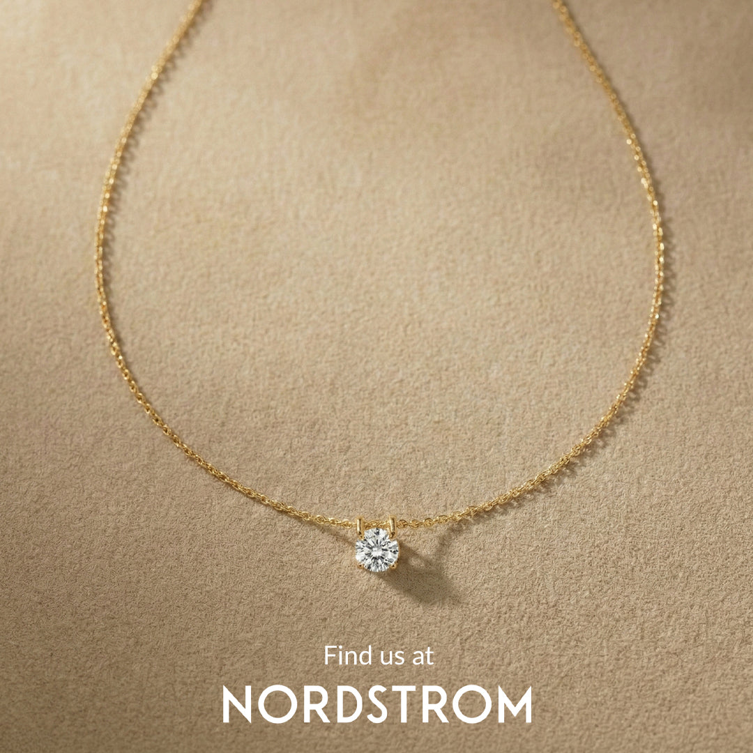 Gold necklace with a diamond pendant on a beige background, featuring Nordstrom branding.