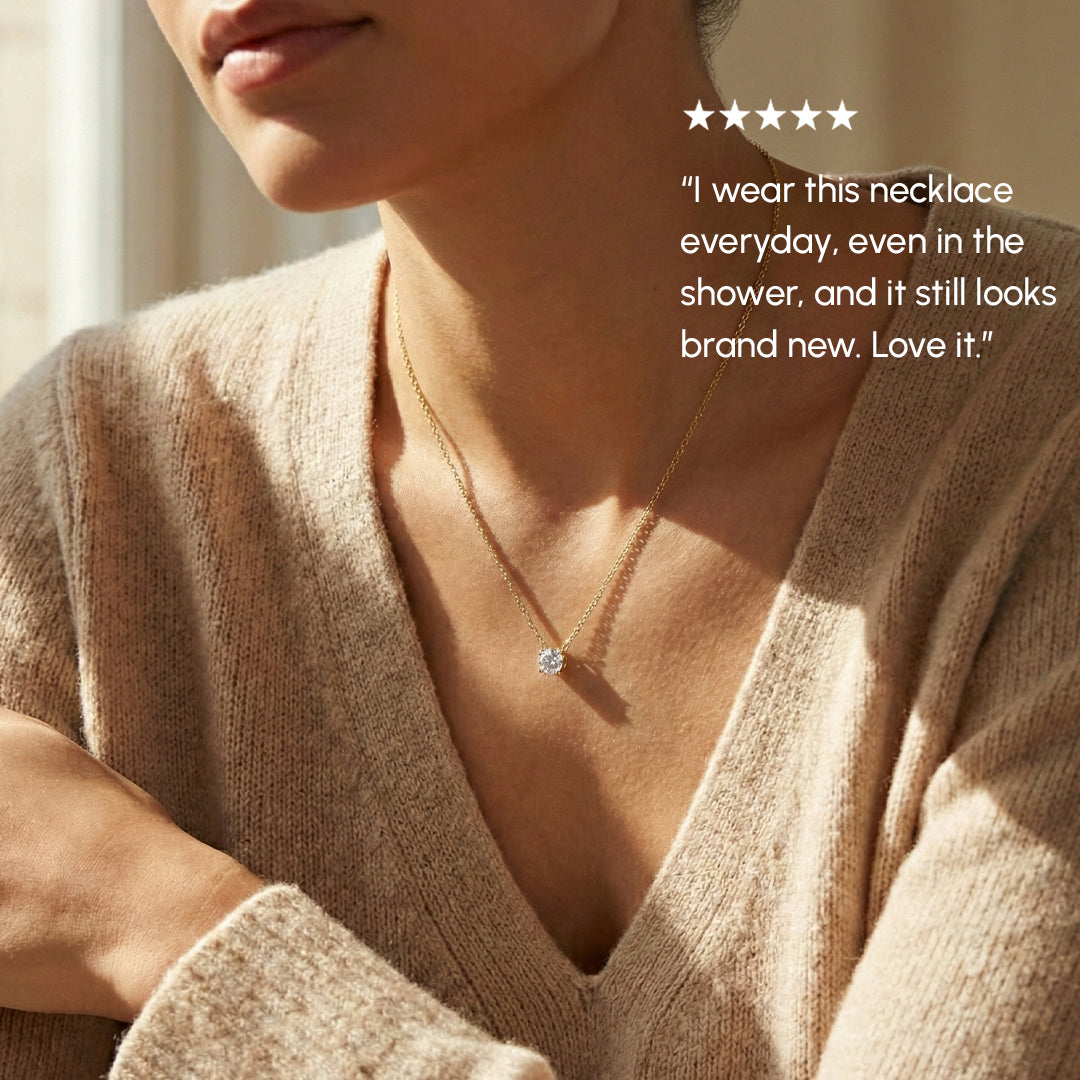 Person wearing a gold necklace with a diamond pendant, set against a neutral background.