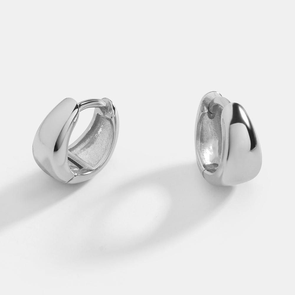 A pair of gold huggie hoop earrings with a teardrop design on a black background.