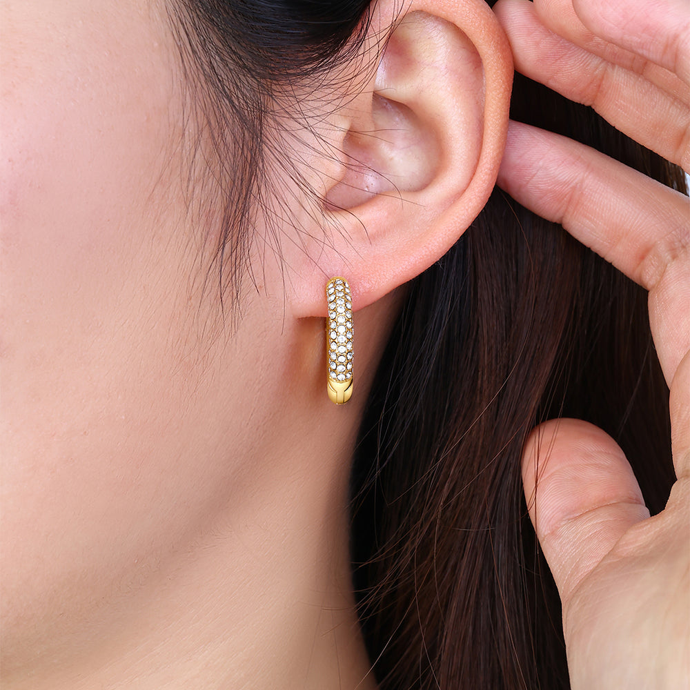 Gold hoop earring being worn and adjusted by a hand