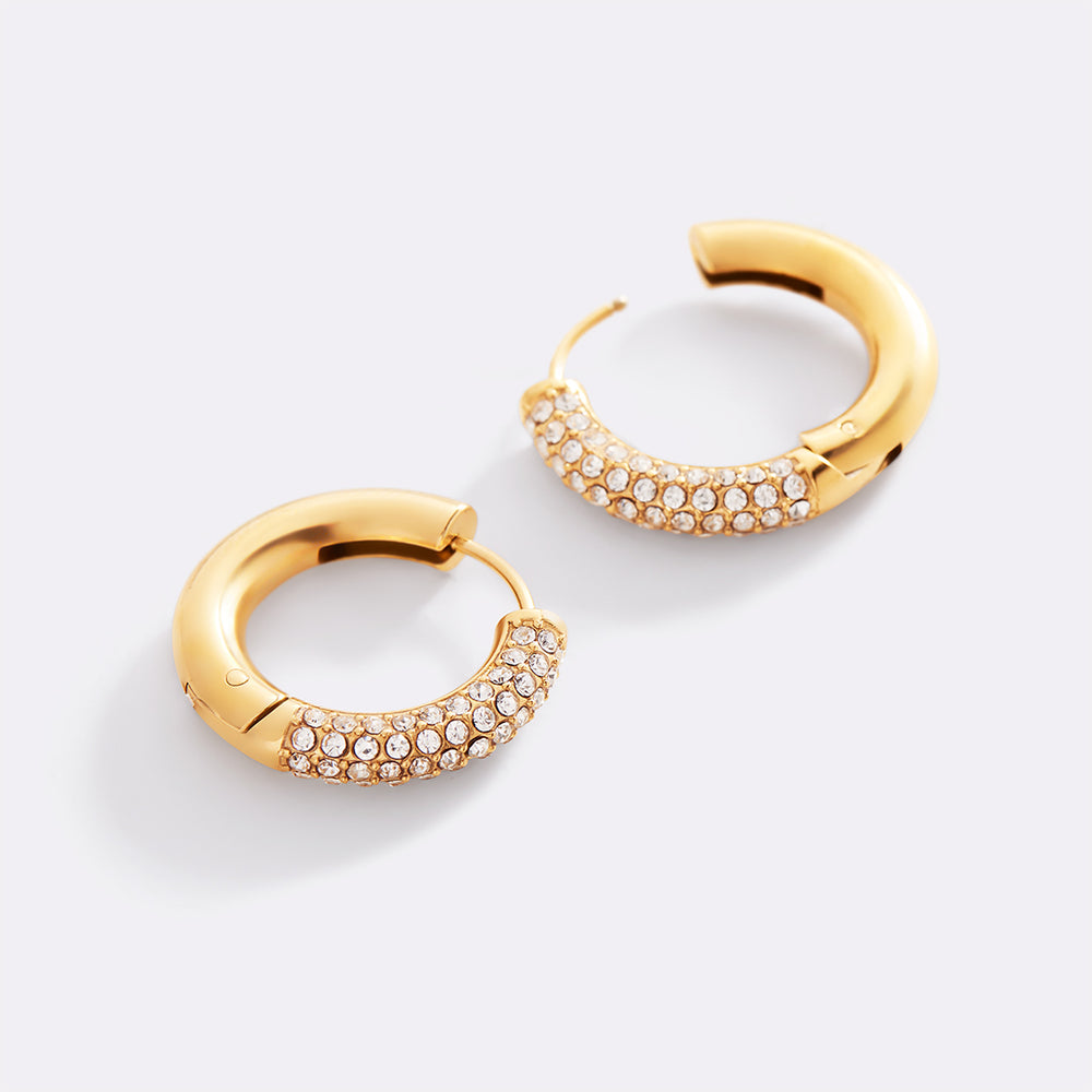 Gold hoop earrings with embedded stones on a light gray background