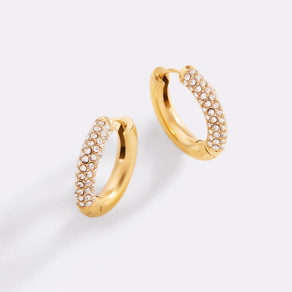 Gold hoop earrings with embedded stones on a light gray background