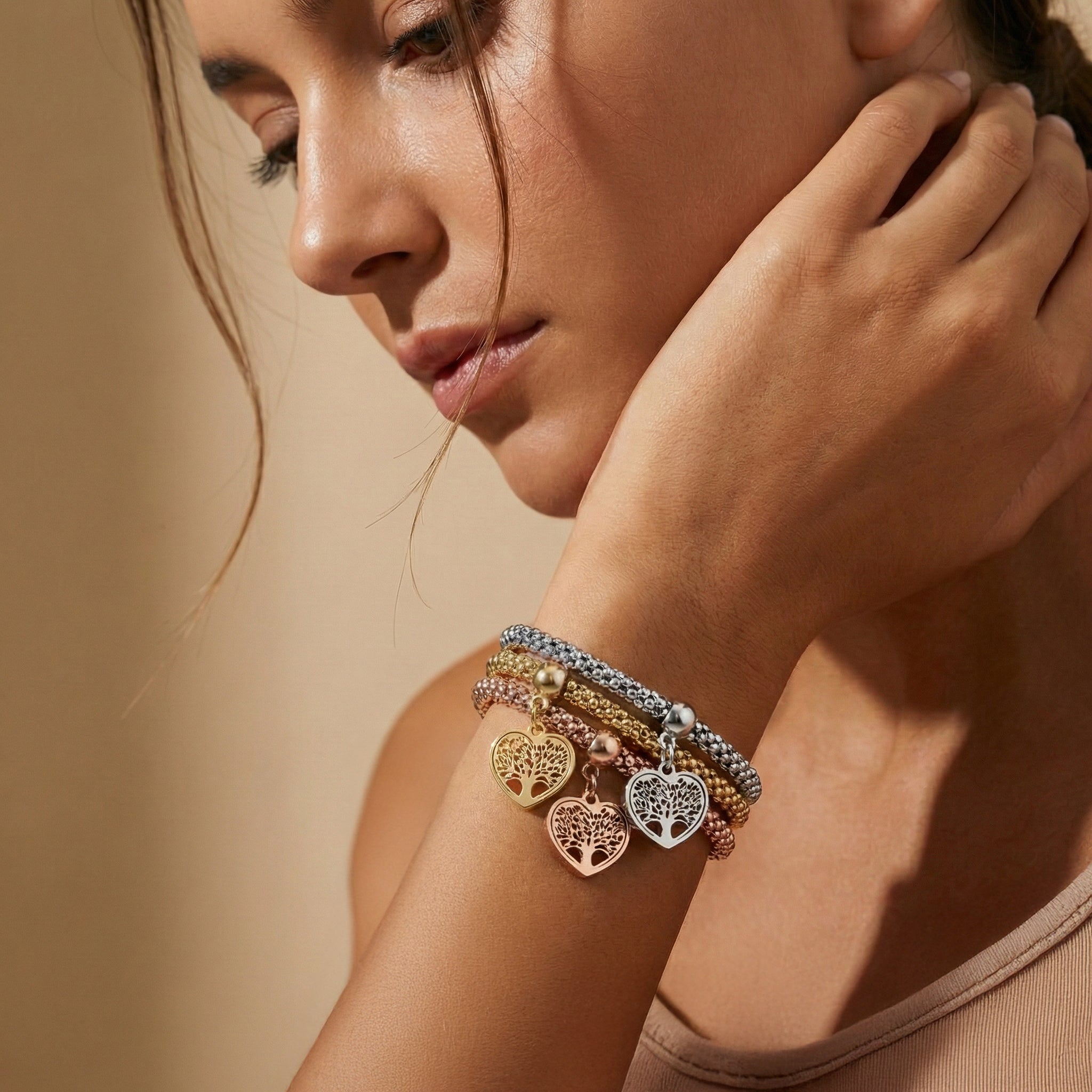 Woman wearing multiple bracelets on her wrist with a neutral background