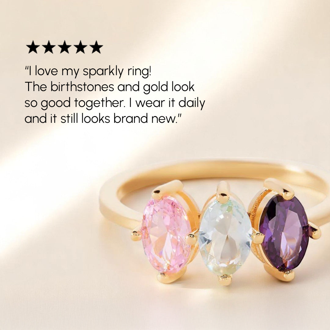 Gold ring with pink, blue, and purple gemstones on a beige background