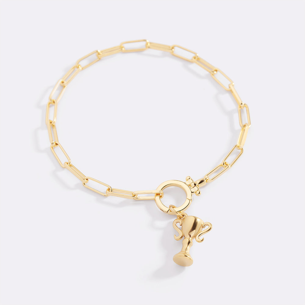 Gold bracelet with a small charm on a light gray background