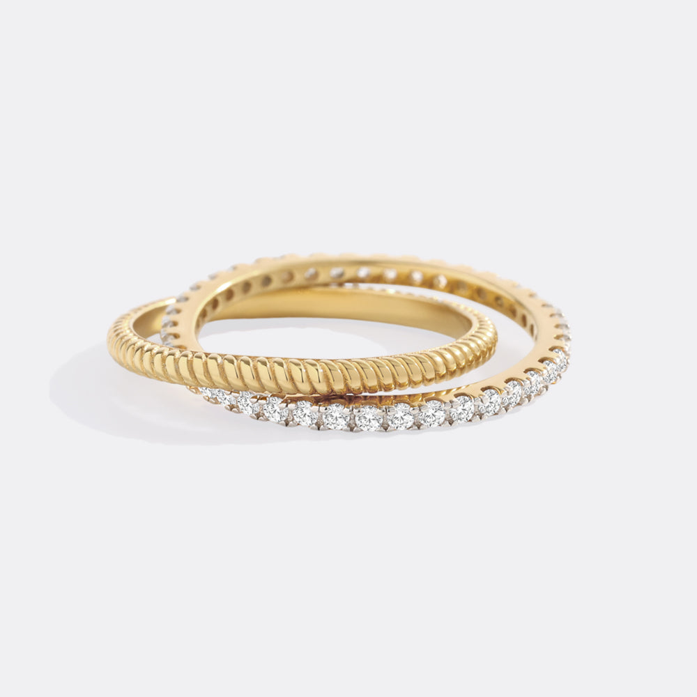 Two gold rings with diamond accents on a light gray background